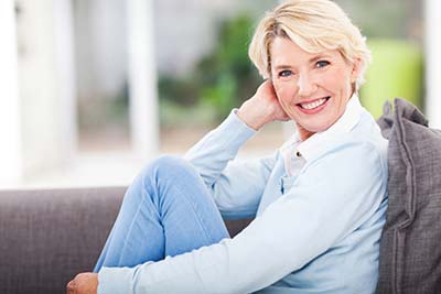 woman with dental implants smiling on the couch
